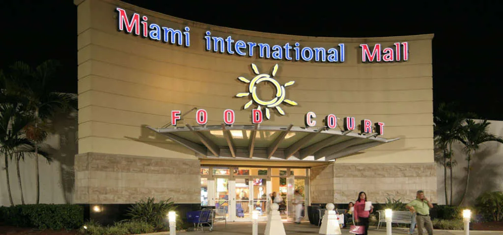 Фасад здания торгового центра Miami International Mall с освещением.