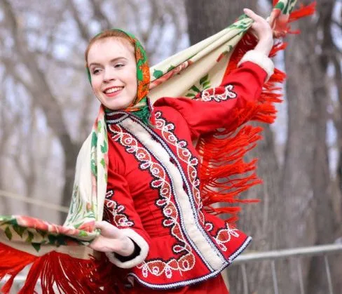 Мужчина и женщина в русских народных костюмах танцуют с платками