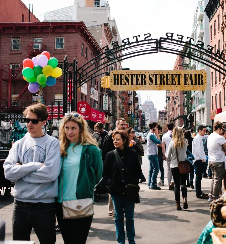 Люди на уличной ярмарке Hester Street Fair под аркой с шарами.