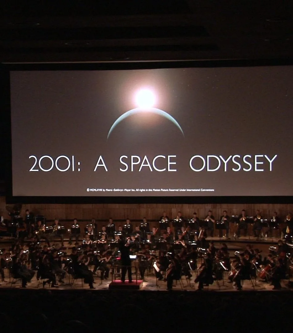 Оркестр выступает перед экраном с надписью 2001: A Space Odyssey.
