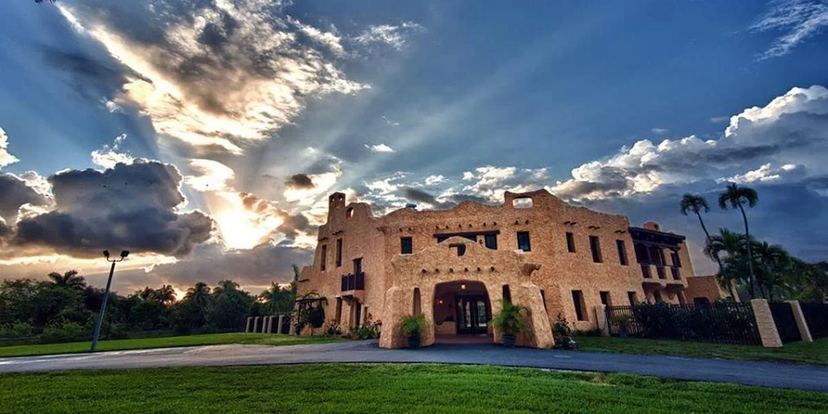 Двухэтажное историческое здание Curtiss Mansion под облачным небом.