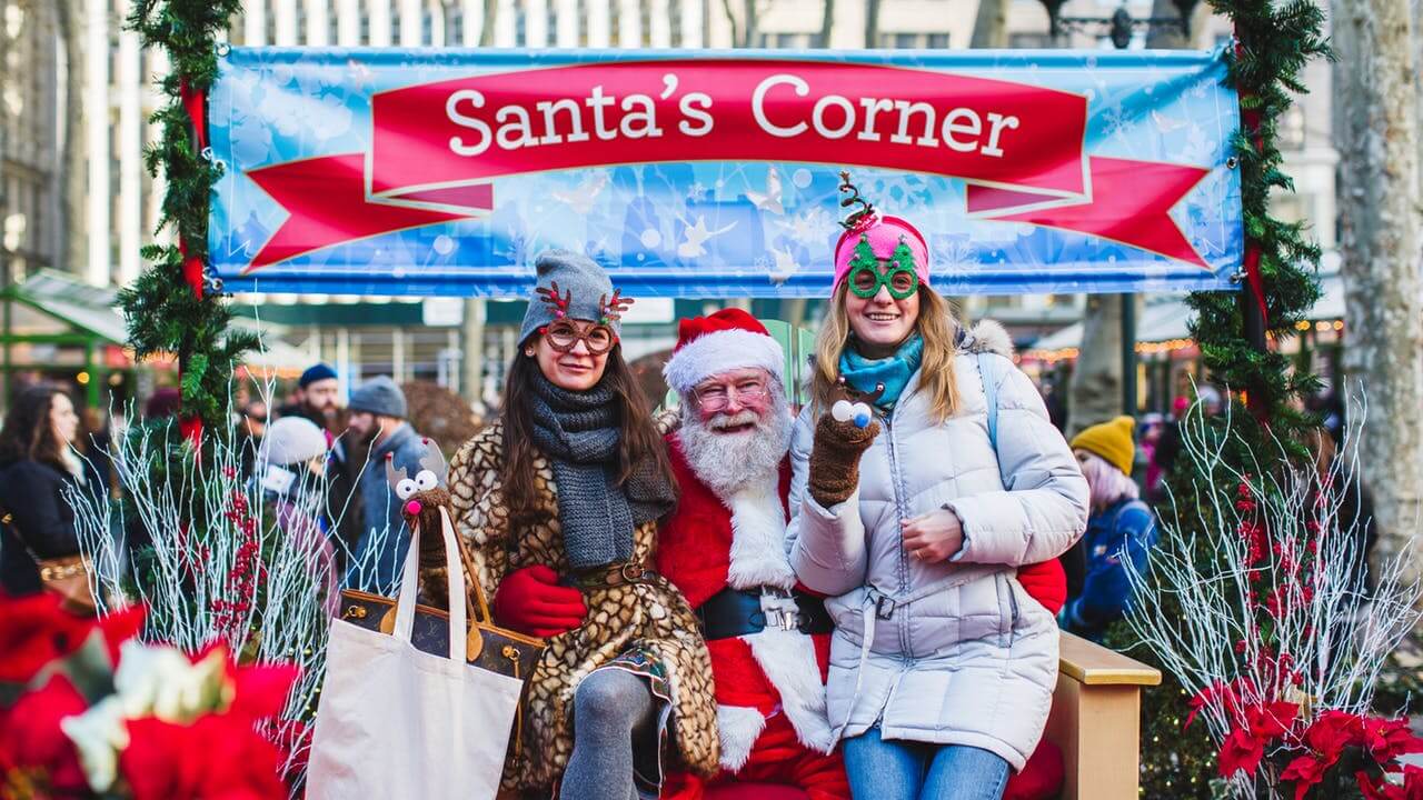 Санта-Клаус сидит с двумя девушками в новогоднем уголке Santa's Corner