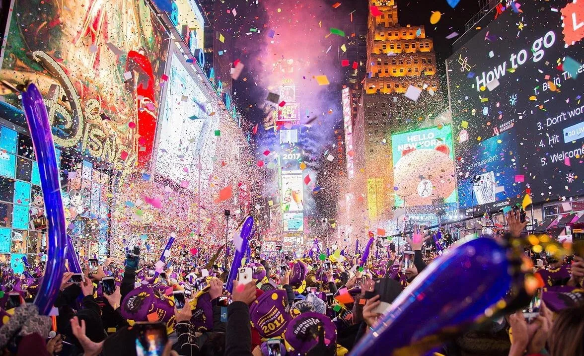 Толпа людей с фиолетовыми шарами празднует Новый год на Таймс-сквер