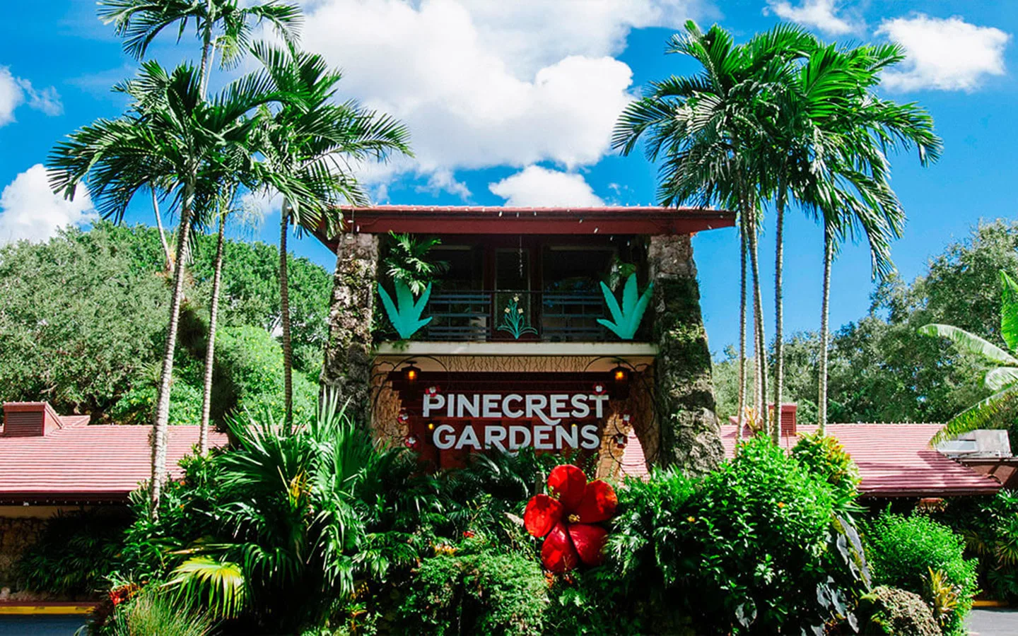 Вывеска Pinecrest Gardens в окружении пальм и пышных растений.