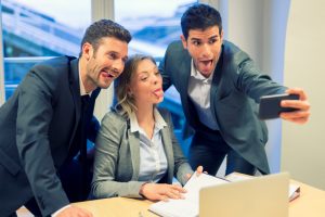 Happy_Workplace_The_One_Thing-Blog-300x200 Selfie business team taking pictures in the office. Their tongue