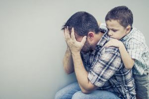 parent-mental-health-issues-300x200 sad son hugging his dad near wall
