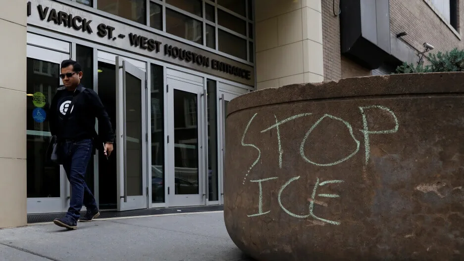 Мужчина выходит из здания иммиграционного суда рядом с надписью Stop ICE.