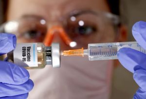 Yahoo-Finance-1-300x204 FILE PHOTO: A woman holds a small bottle labeled with a "Vaccine COVID-19" sticker and a medical syringe in this illustration