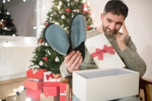 istockphoto-1032296244-612x612-300x200 Caucasian man opening a Christmas present with disappointment.