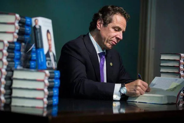 Эндрю Куомо подписывает экземпляры своей книги за рабочим столом