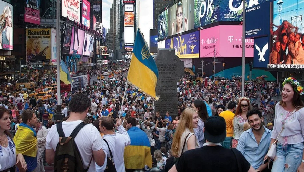 Толпа людей с украинскими флагами на площади Таймс-сквер в Нью-Йорке.