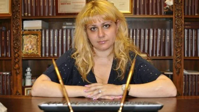 Илона Джамгарова за рабочим столом на фоне книжных полок