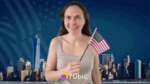 Улыбающаяся женщина держит маленький флаг США на фоне силуэта Нью-Йорка.
