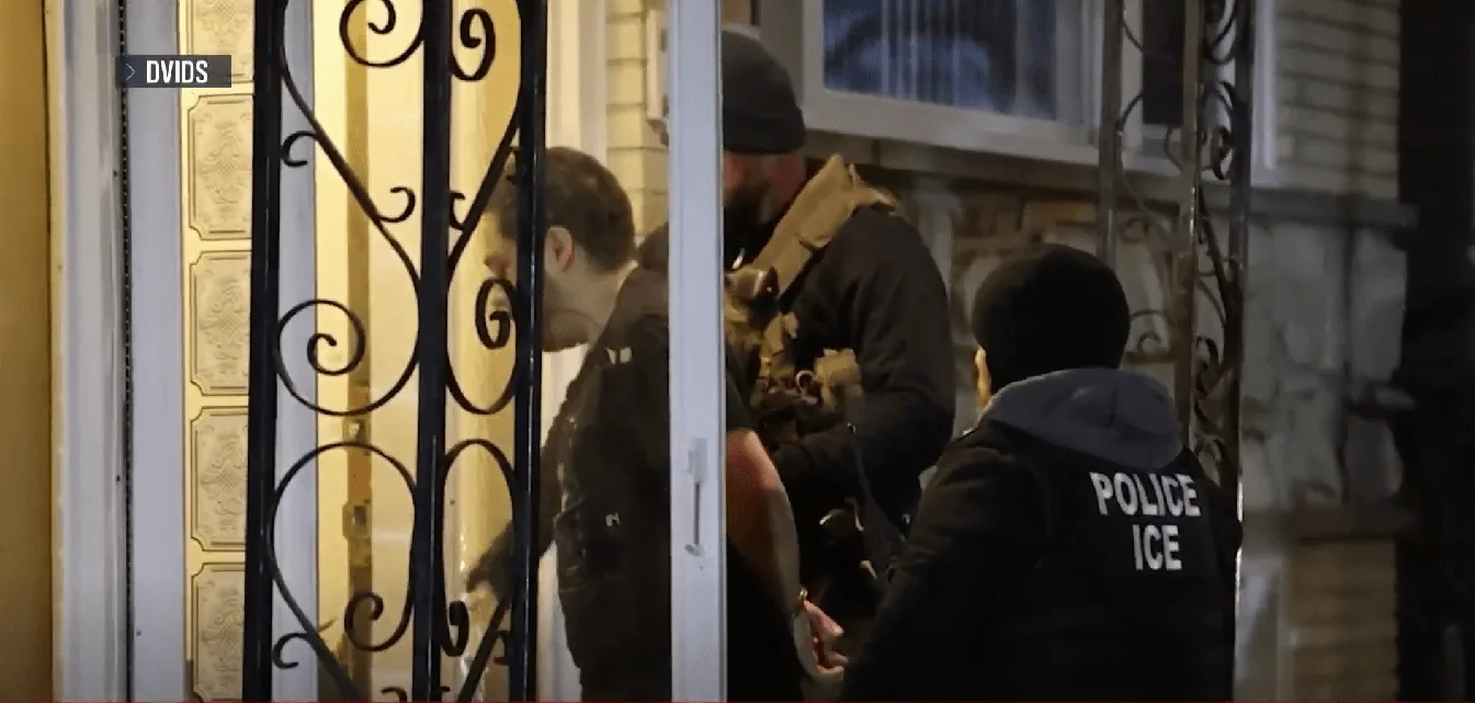 Агенты ICE задерживают мужчину у дверей жилого дома.